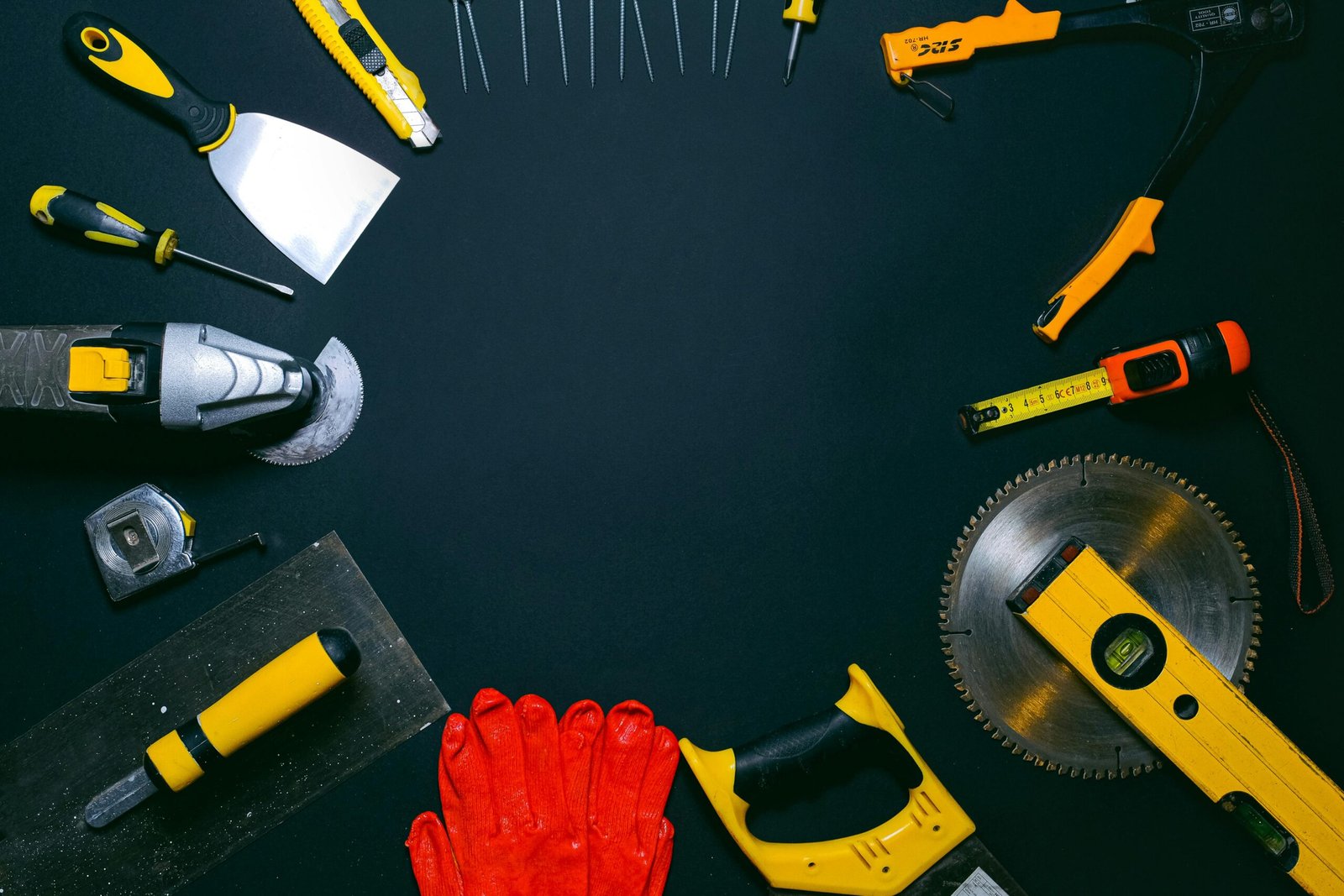 A collection of hand tools laid out on a dark surface, perfect for construction themes.